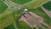 Deze afbeelding toont een dalbodemberging, een specifieke vorm van waterbeheersing waarbij een natuurlijk dal of beekdal wordt gebruikt om tijdelijk grote hoeveelheden water op te slaan.