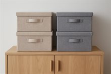 Vier opbergboxen staan op een houten kast. De spullen zijn zo hoger opgeborgen om ze te beschermen tegen wateroverlast.